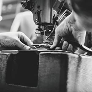 Black and white picture with hands and sewing machine.