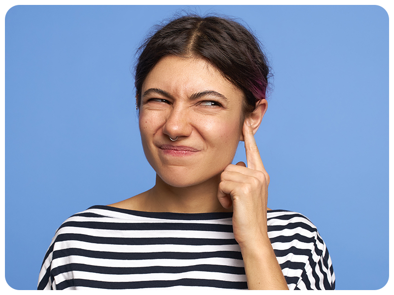 person suffering from ear pain and itchiness and scratching their ear