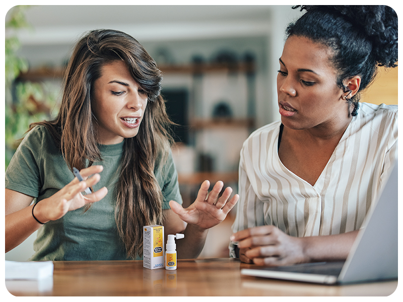 two people at a table with a bottle of wax remover for ears on the table