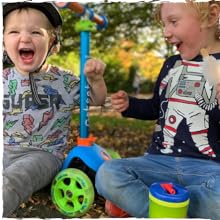 Young boy riding a blue trunki scooter in a park