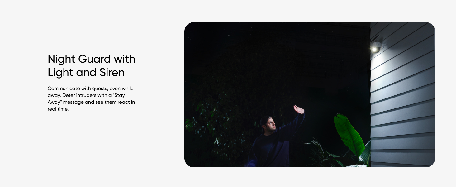 Night guard device with light and siren installed on exterior wall, illuminating dark area near plants.