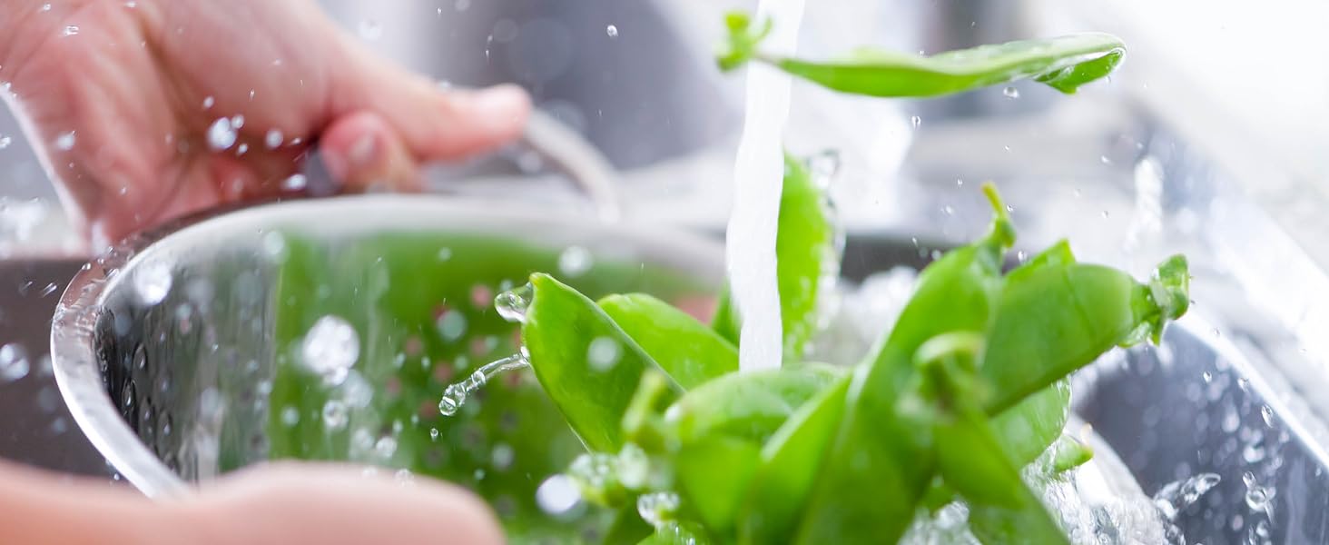 A colander of Green Beans being rinsed with cold water