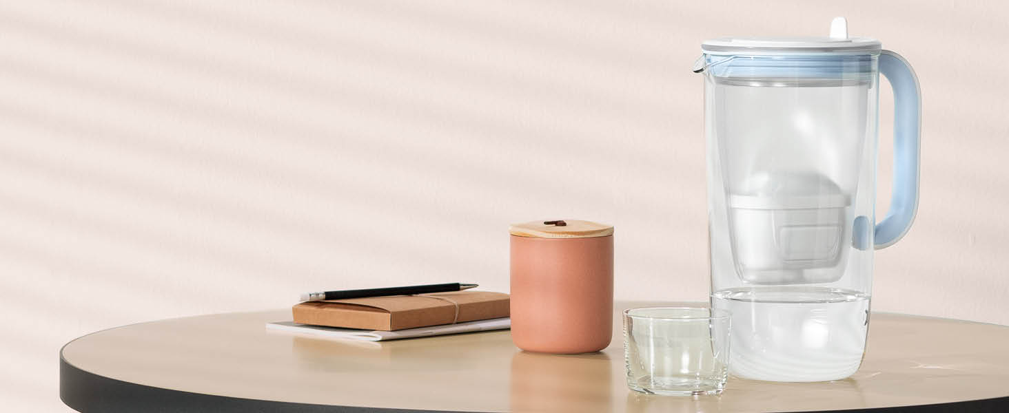 A BRITA Glass Jug on a table next to a glass of water