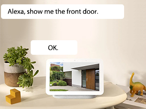 Smart home interface showing dialog box with text 'Alexa, show me the front door' against a light beige background with home interior elements.