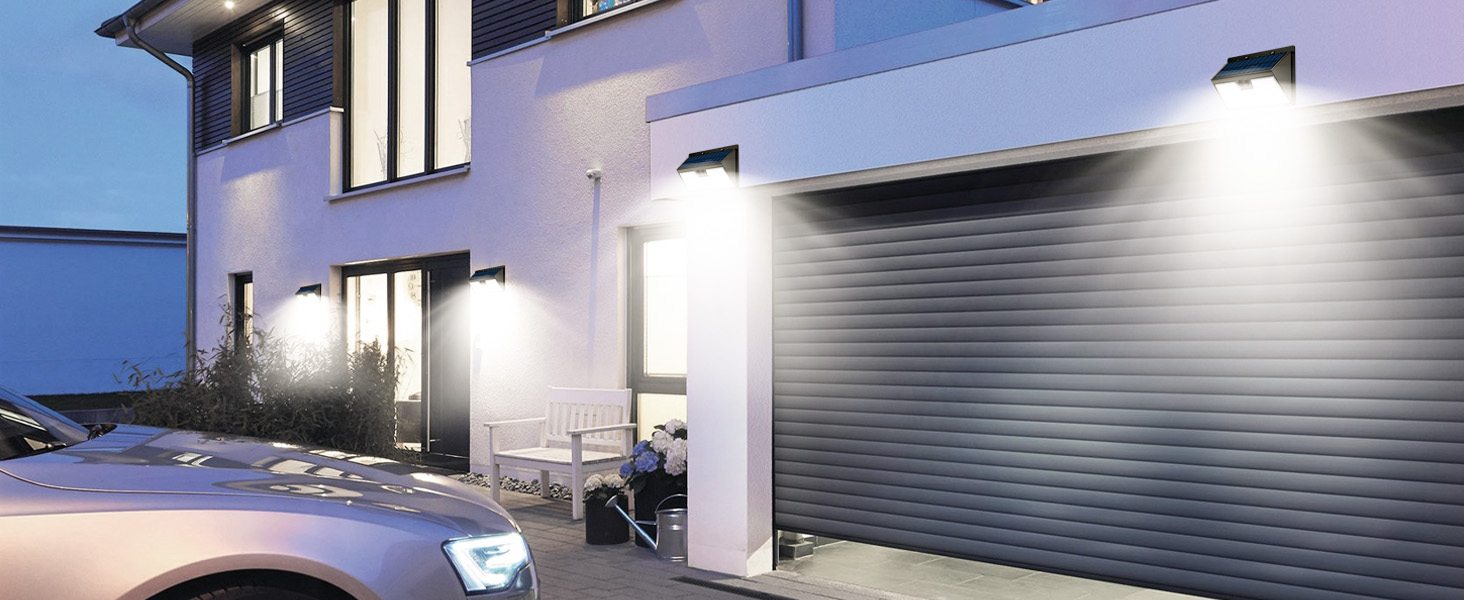 Exterior wall-mounted security lights illuminating a commercial building facade and garage door area at night.