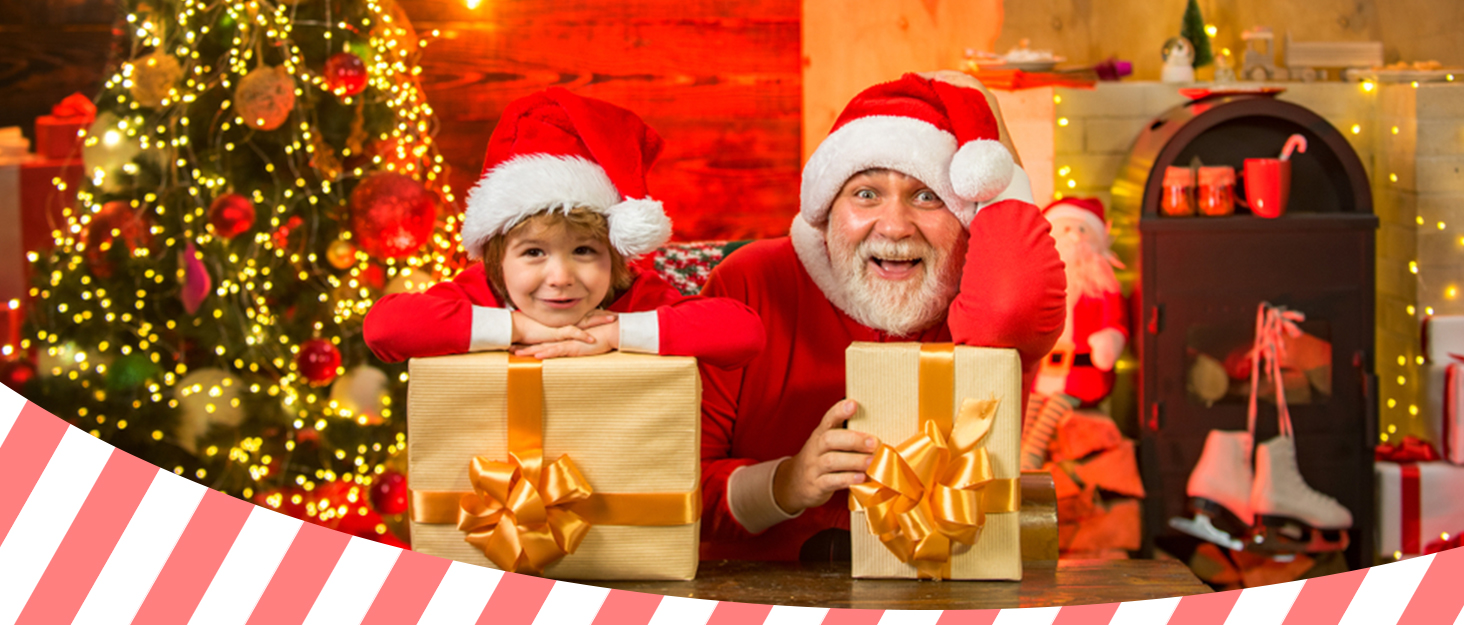 Christmas scene with decorated tree, presents, and festive background. Two figures in Santa hats hold wrapped gifts with gold bows.