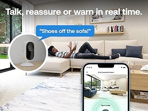 Text reads: 'Talk, reassure or warn in real time.' and 'Shows off the sofa!'. Smart home setup showing security camera view on smartphone with living room interior.