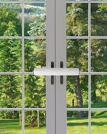 White French doors with glass panes, leading to a lush green garden view. Black handles visible on both doors.