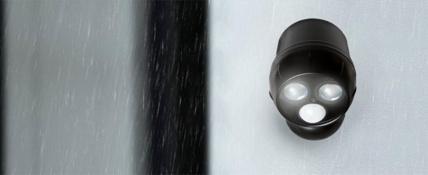 Black spherical device with three bright LED lights mounted on a wall. Rain or water droplets visible in the foreground.