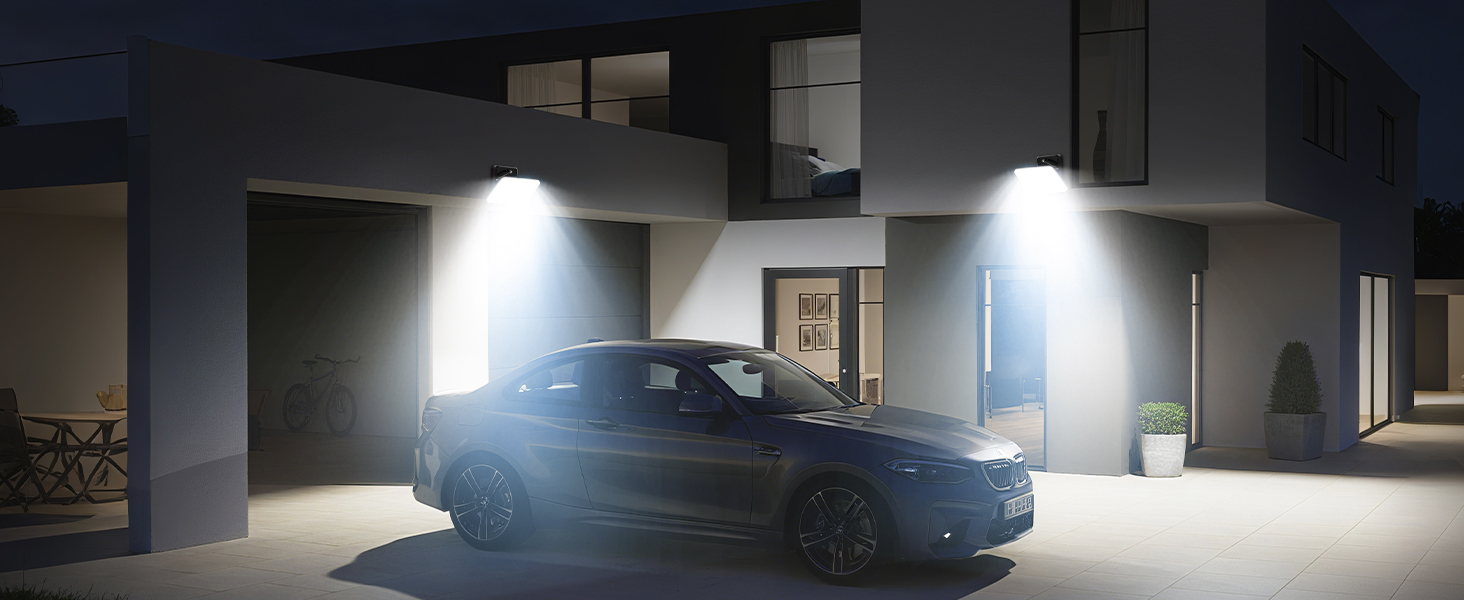 Dark industrial or warehouse setting showing LED light fixtures mounted on ceiling or walls, demonstrating bright white illumination in the space.