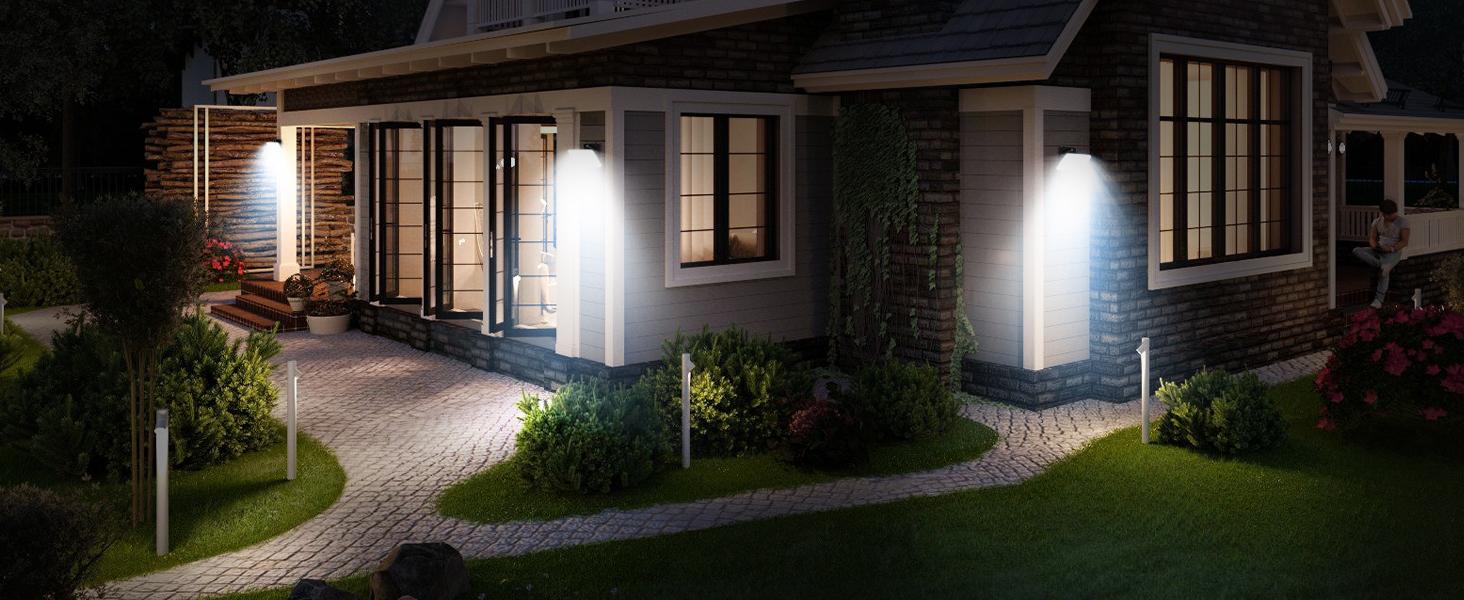 Exterior nighttime view of house with illuminated pathway lights along walkway and near entrance, creating pools of white light on ground.