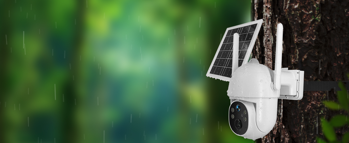 White security camera mounted on outdoor wall or tree, with blurred green foliage in background.