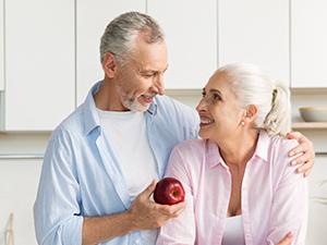 Beagle dog and orange cat resting together on light-colored carpet, with white furniture and houseplant visible in background.