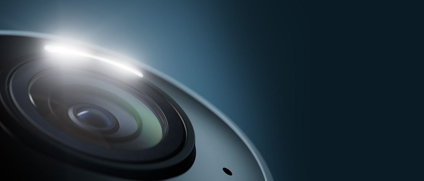 Professional camera lens shown in dramatic lighting against dark background, highlighting curved glass elements
