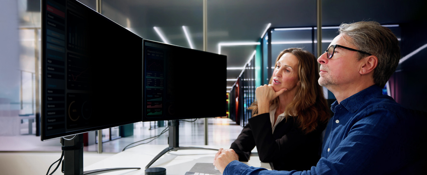 Professional office setting showing people working at computer monitors in modern workspace environment with ambient lighting.