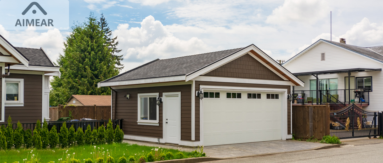 Single-story residential home with white garage door, gray roof, and maintained front lawn, photographed in daylight.