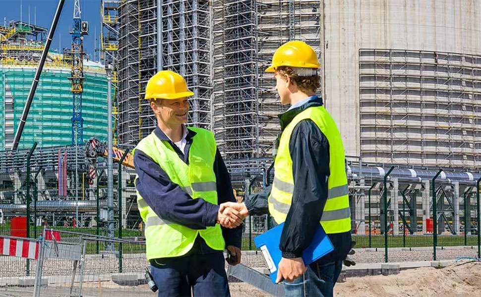two construction workers shaking hands in front of a building