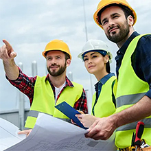 two people in a yellow vests looking at a car engine