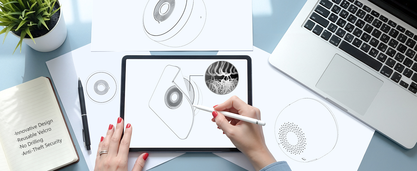 Overhead view of desk workspace showing hands working with documents, laptop, and circular diagram sketches or drawings.