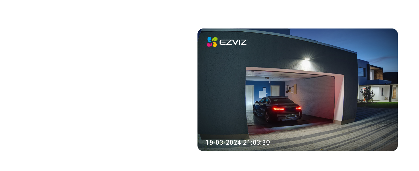 Night view of a house with an illuminated garage. A red car is visible inside the open garage door.