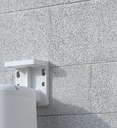 White cylindrical device mounted on a gray stone wall, with 'reolink' branding visible. Partially blurred background suggests outdoor setting.