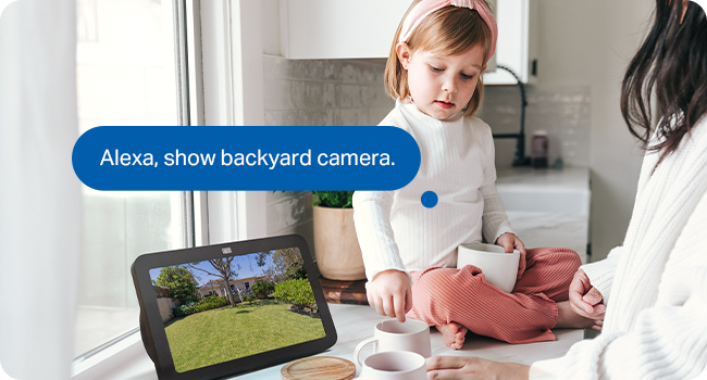 Text reads 'Alexa, show backyard camera.' Person interacting with a smart device or screen displaying interface controls.