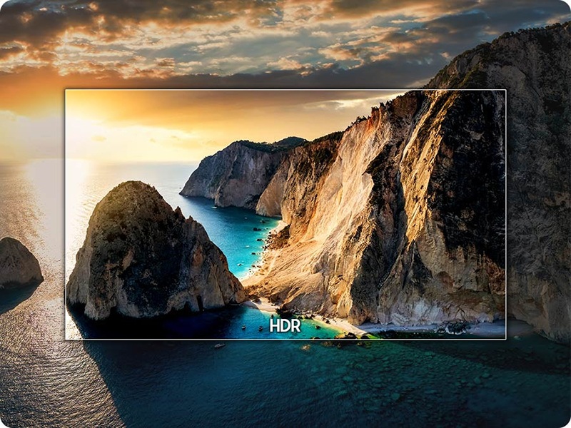 High-definition display screen showing scenic coastal landscape with dramatic rocky cliffs, turquoise ocean water, and golden sunset sky. Text reads 