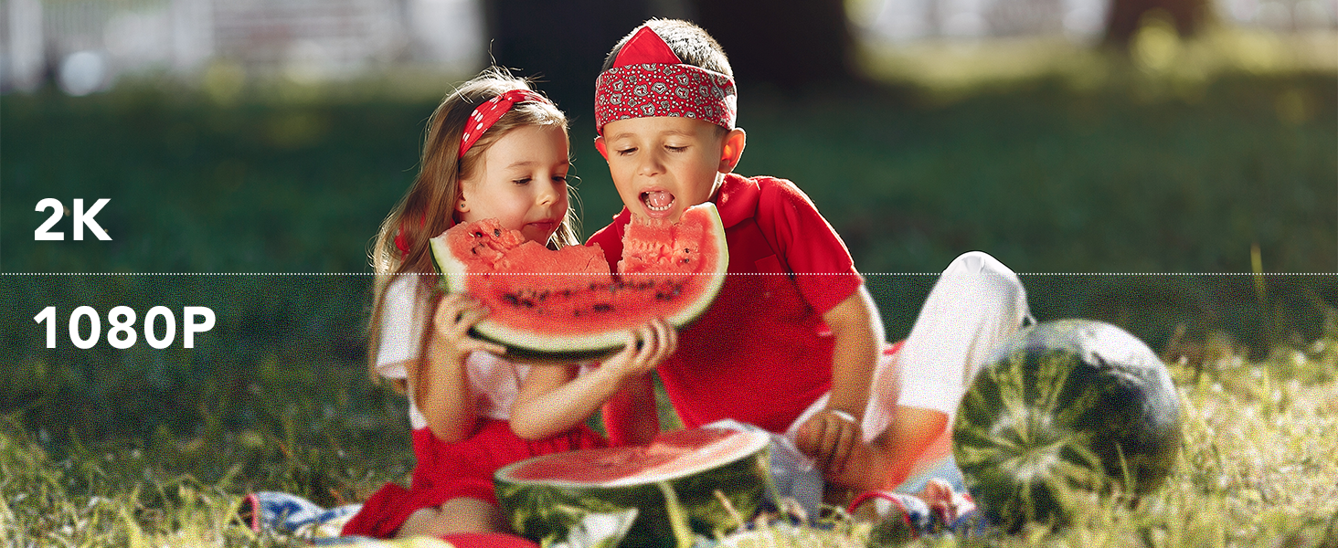 Text reads '2K 1080P'. Two young children in red and yellow clothing sitting on grass outdoors, demonstrating video resolution quality.