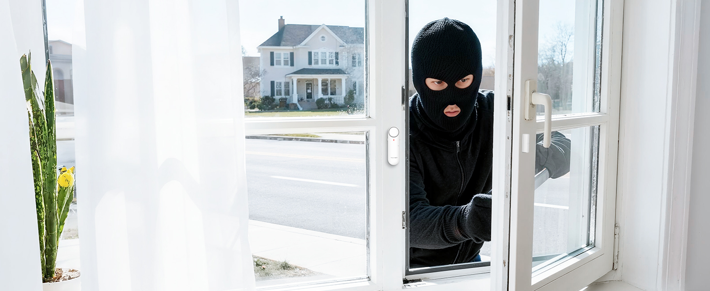 View through window showing person in black ski mask attempting to enter, suggesting home security context. White house visible in background.