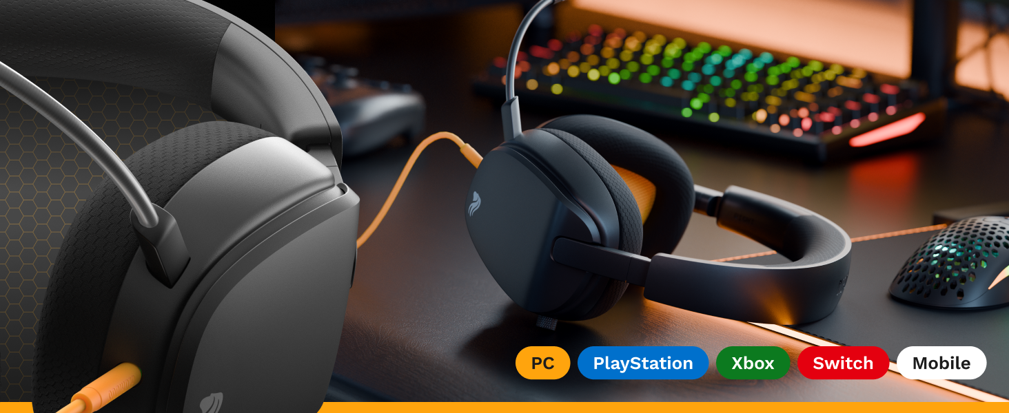 Gaming or computer setup showing dark-colored headphones against RGB backlit keyboard in low-light environment.