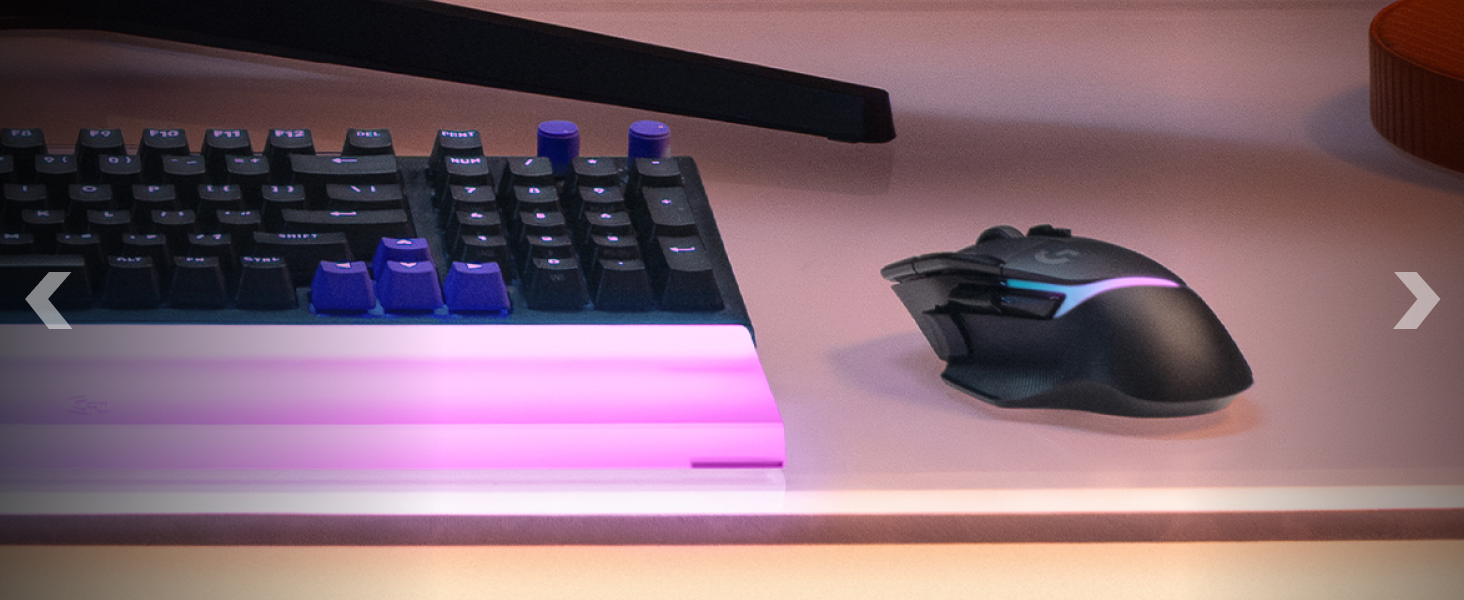 RGB illuminated keyboard and mouse setup on dark surface with purple-pink ambient lighting.