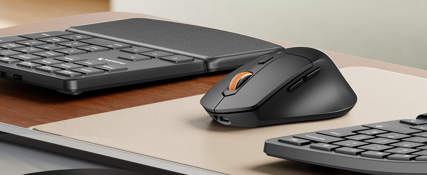 Wireless computer mouse in matte black, with ergonomic shape and visible side buttons, positioned between two partial keyboard views on a desk surface.
