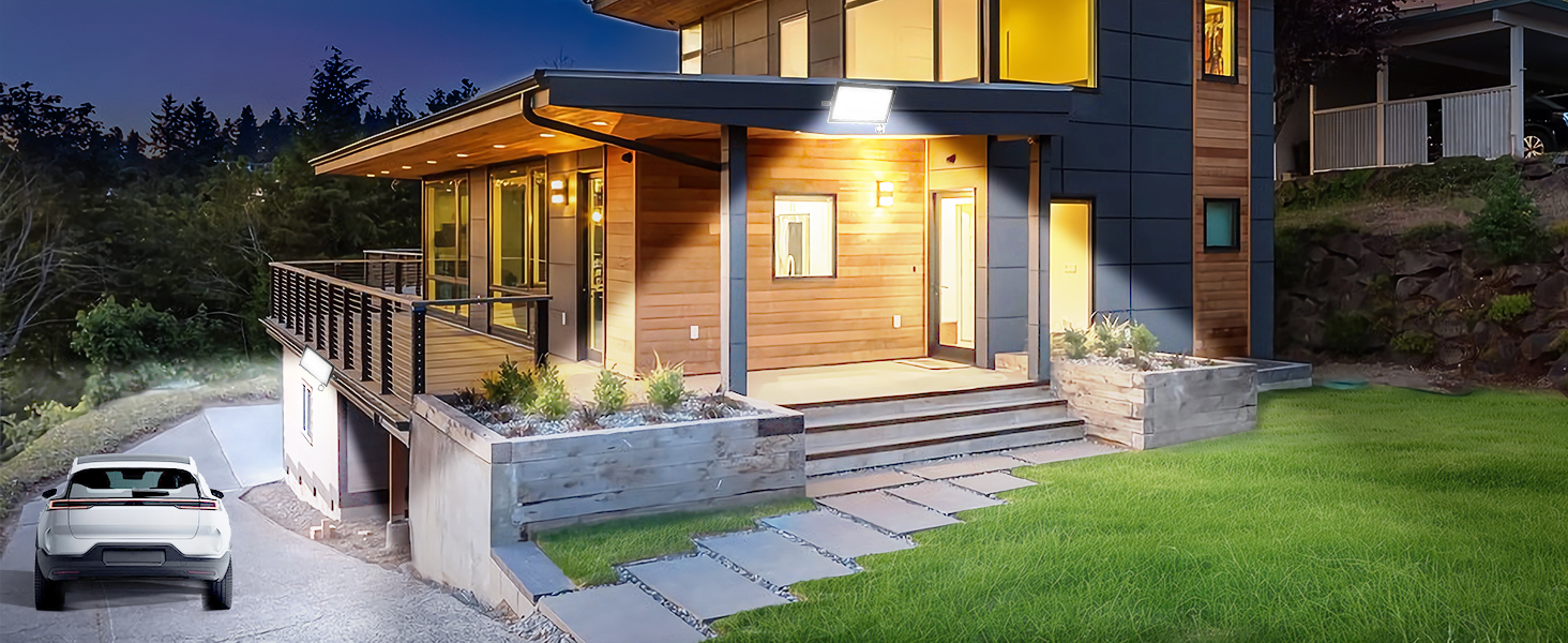 Modern house exterior at dusk with illuminated entrance, wooden accents, concrete steps, and landscaped yard.