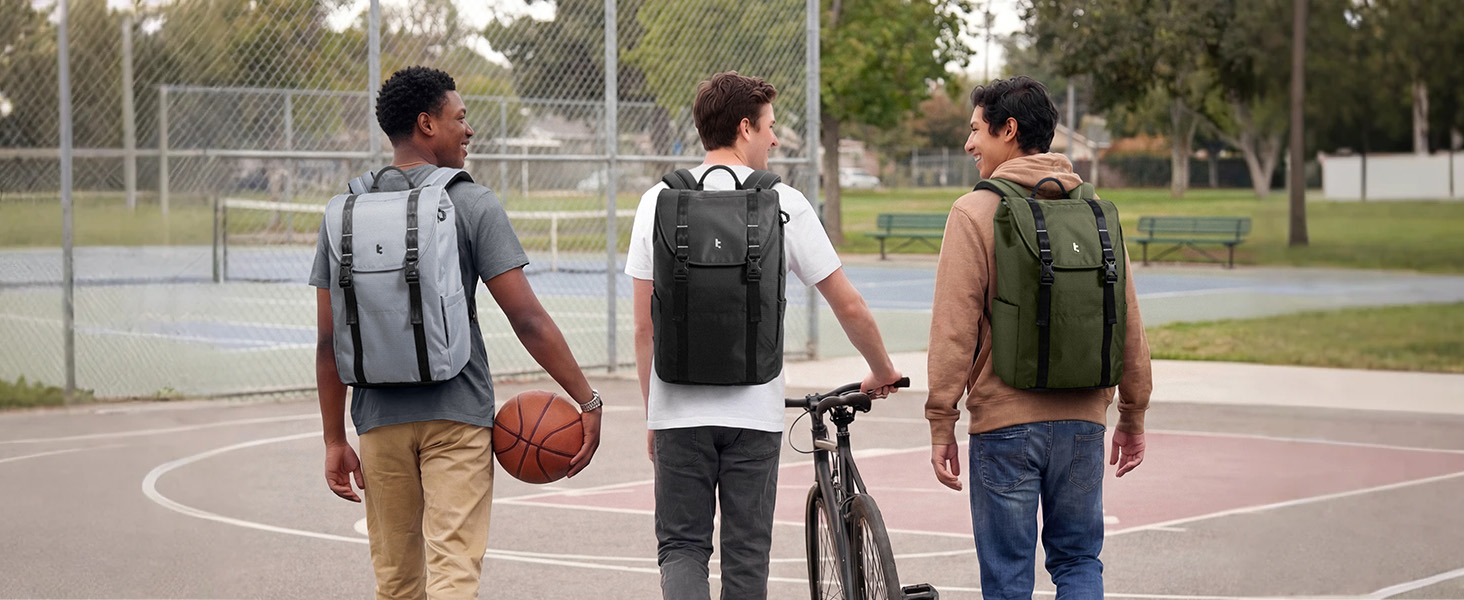 Three young people standing outdoors on a basketball court, each wearing different colored backpacks (gray, black, and brown) while holding a basketball and bicycle.