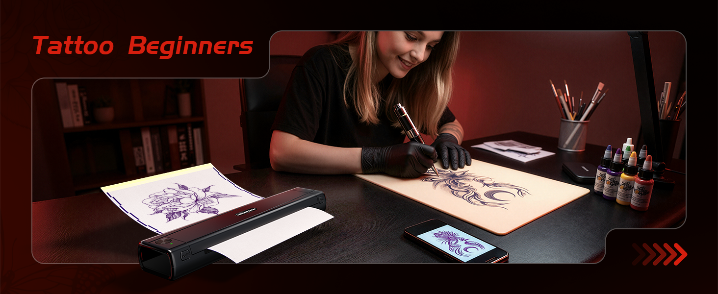 Text reads 'Tattoo Beginners.' Two people working on tattoo designs at table with sketches, equipment, and supplies visible in studio setting.