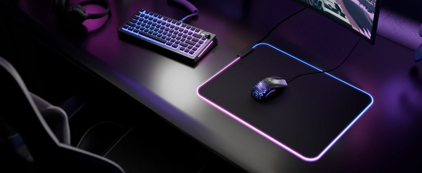 Gaming desk setup in dark lighting with illuminated mousepad and computer mouse on desk surface.