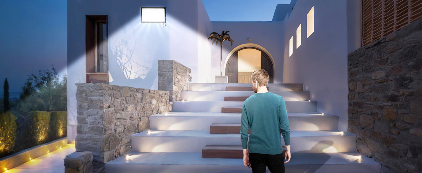Outdoor night scene with illuminated steps and archway. Person in teal shirt walking up stone stairs towards lit entrance.
