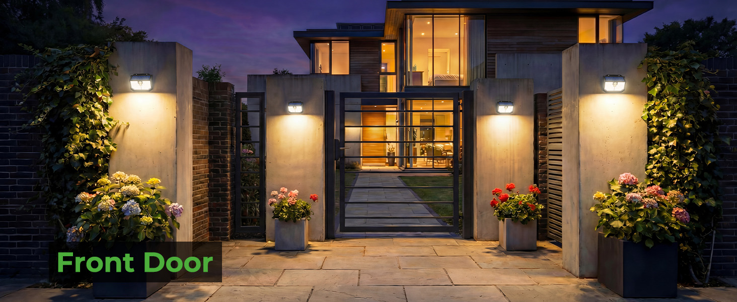 Text reads: 'Front Door'. Modern home entrance at dusk with symmetrical outdoor wall lights, wooden and glass door, and decorative potted flowers on either side of stone steps.