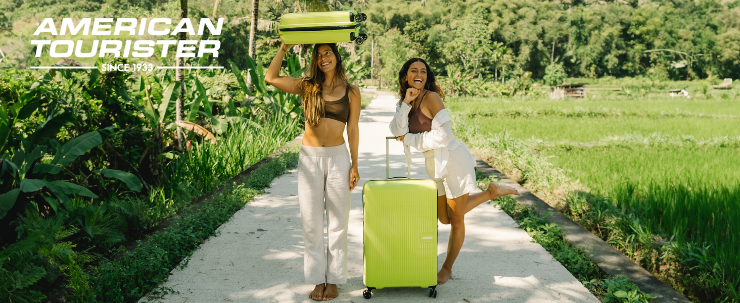 Bright lime green hardshell luggage being rolled along a sunny outdoor pathway through a garden setting.