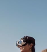 Drone flying in clear sky, captured from below against light gray background.