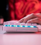 Full-size mechanical keyboard with backlit keys in blue/teal lighting against dark background. Shows complete keyboard layout with illuminated keycaps.