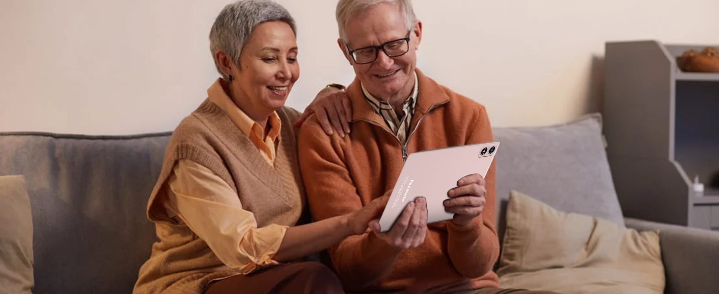White tablet device being used by two people sitting on a couch. The tablet has a smooth, rectangular design with visible screen and appears to be the focus of their attention.
