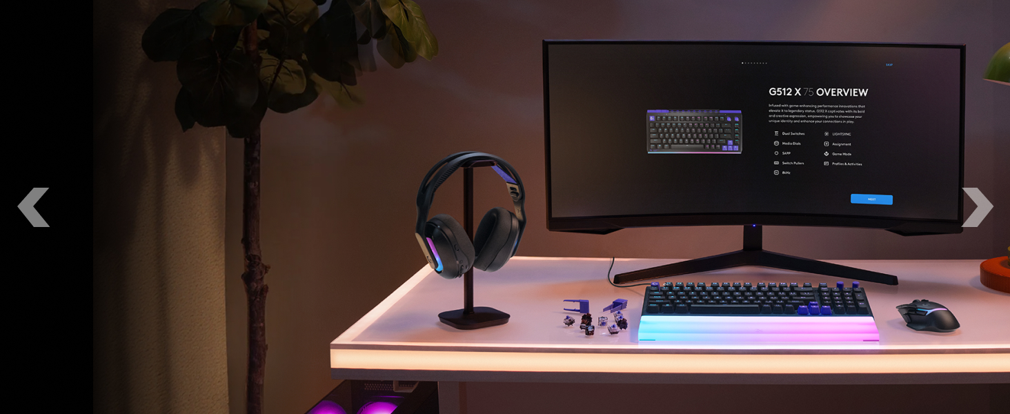 Desktop setup in dark lighting showing multiple monitors, keyboard, and LED lighting strips creating ambient purple/pink illumination along the desk and wall.