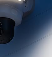 Close-up view of a security or surveillance camera mounted on a ceiling or wall against a dark blue background.