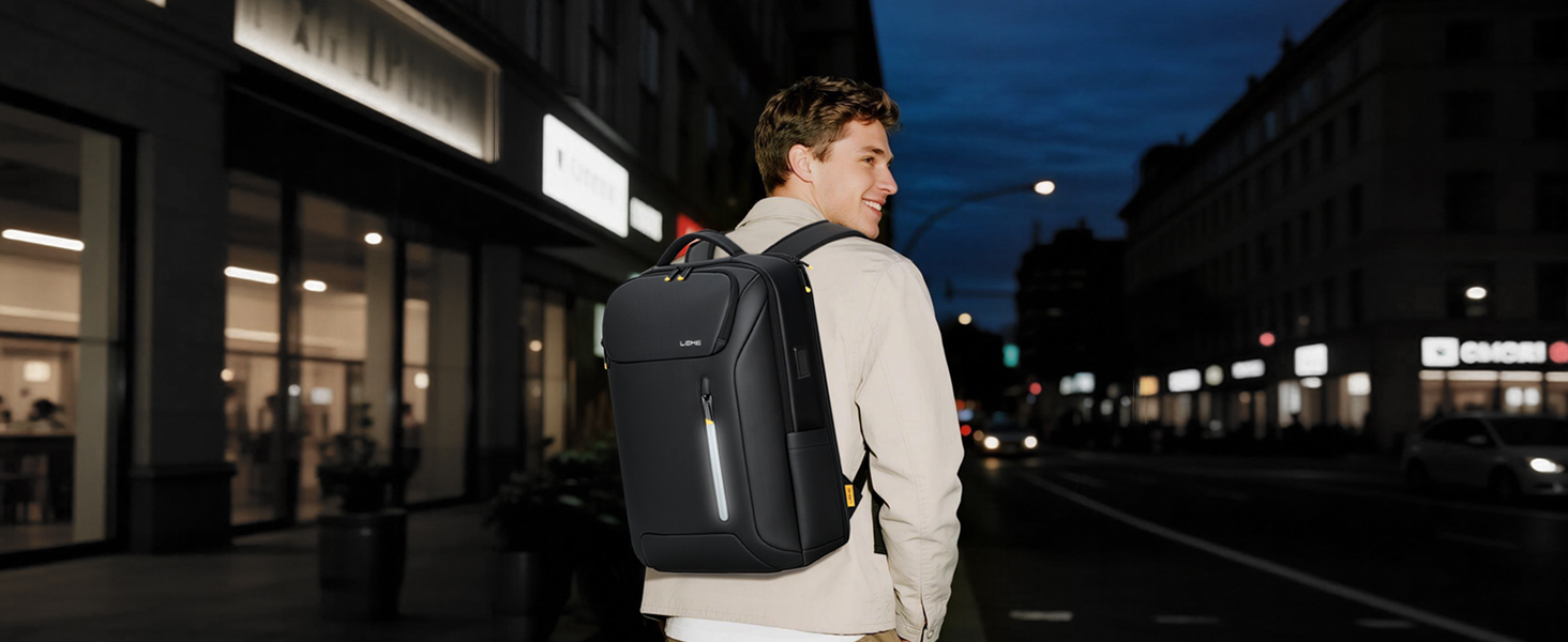 Person wearing black and white athletic outfit with dark backpack standing on train platform at dusk in urban setting.