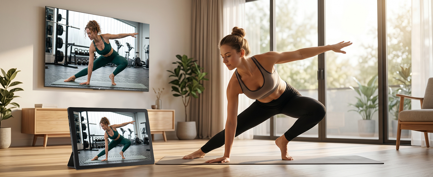 Woman performing yoga/exercise pose in bright minimalist living room with large window. Scenes displayed on mounted TV and tablet screen showing fitness content and workout guidance.
