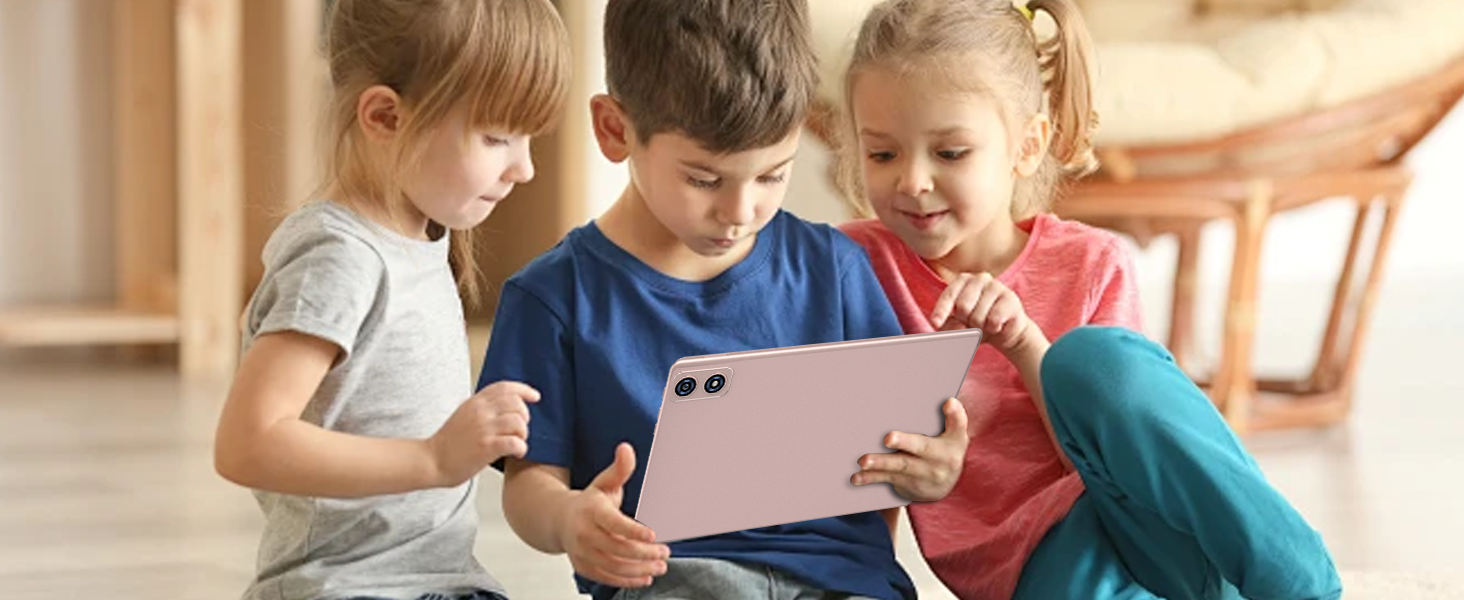 Three children sitting on a floor, engaged with a large pink tablet device. The tablet appears to have a dual camera system visible on its back.