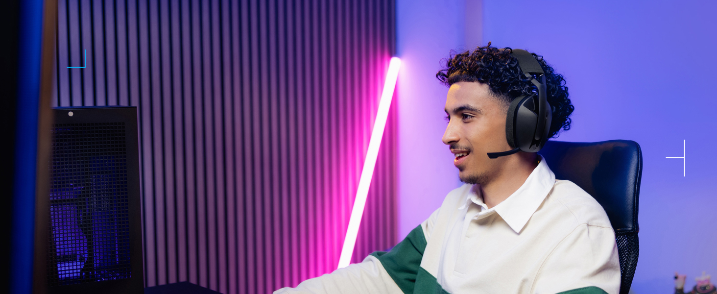 Gaming or streaming setup with neon pink lighting and vertical wall panels. Person wearing headset seated at desk with illuminated background.