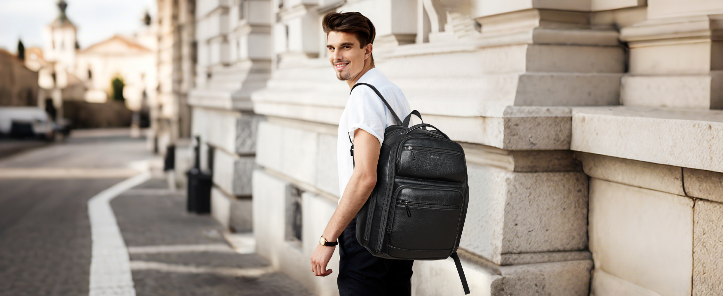 Person wearing black backpack shown from behind while standing next to stone wall in urban setting during daytime.