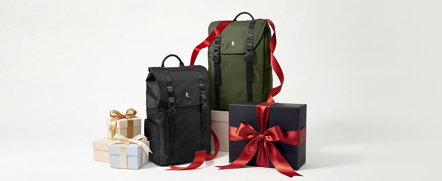 Olive-green backpack with red accents positioned among gift boxes, decorative wrapped presents, and holiday accessories against neutral background.